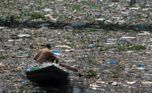a man in a boat in a dirty, polluted river