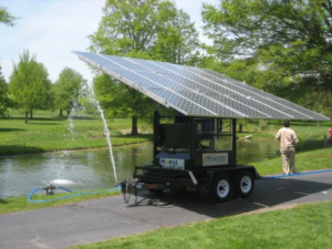 A solar-powered water pump operates to supply clean water to a pond, highlighting renewable energy use in agriculture.