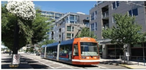 A tram is on the tracks, with buildings in the background, which illustrates sustainable transportation