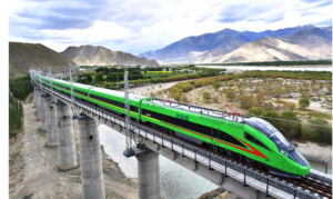 A green and red high-speed train crosses a bridge, 