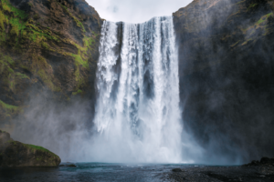 A serene waterfall cascades into a river, surrounded by lush greenery and natural beauty. 